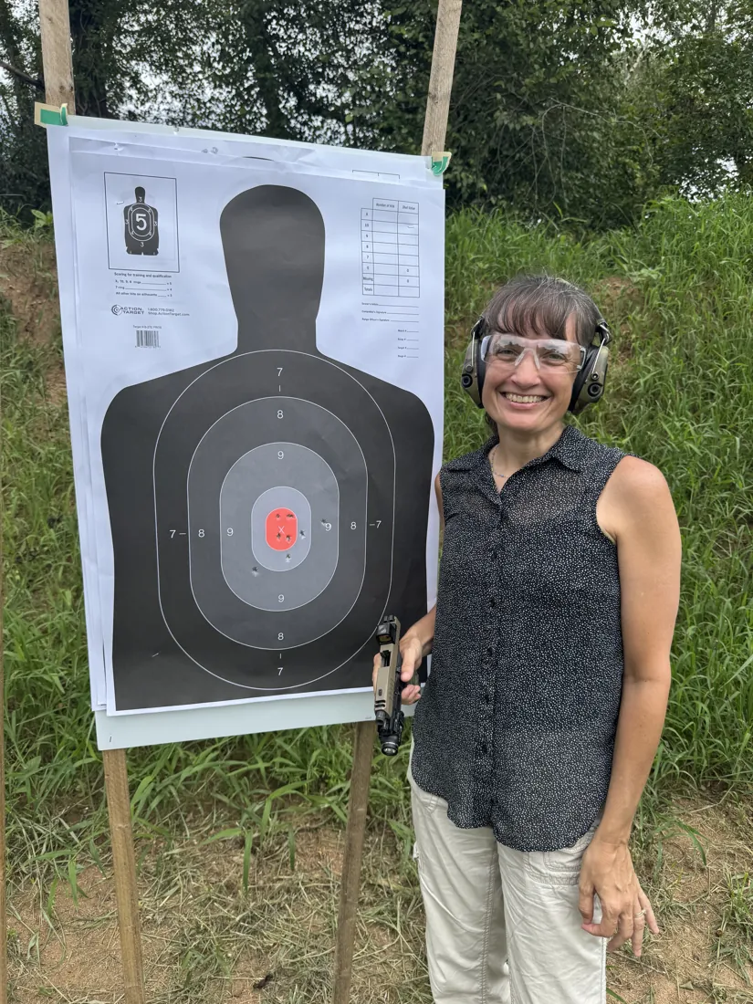 A student smiling next to her target after a training session